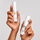 Mains tenant les sérums Forever Vitamin C™ et Forever Bakuchiol™ pour une routine de soin quotidienne-