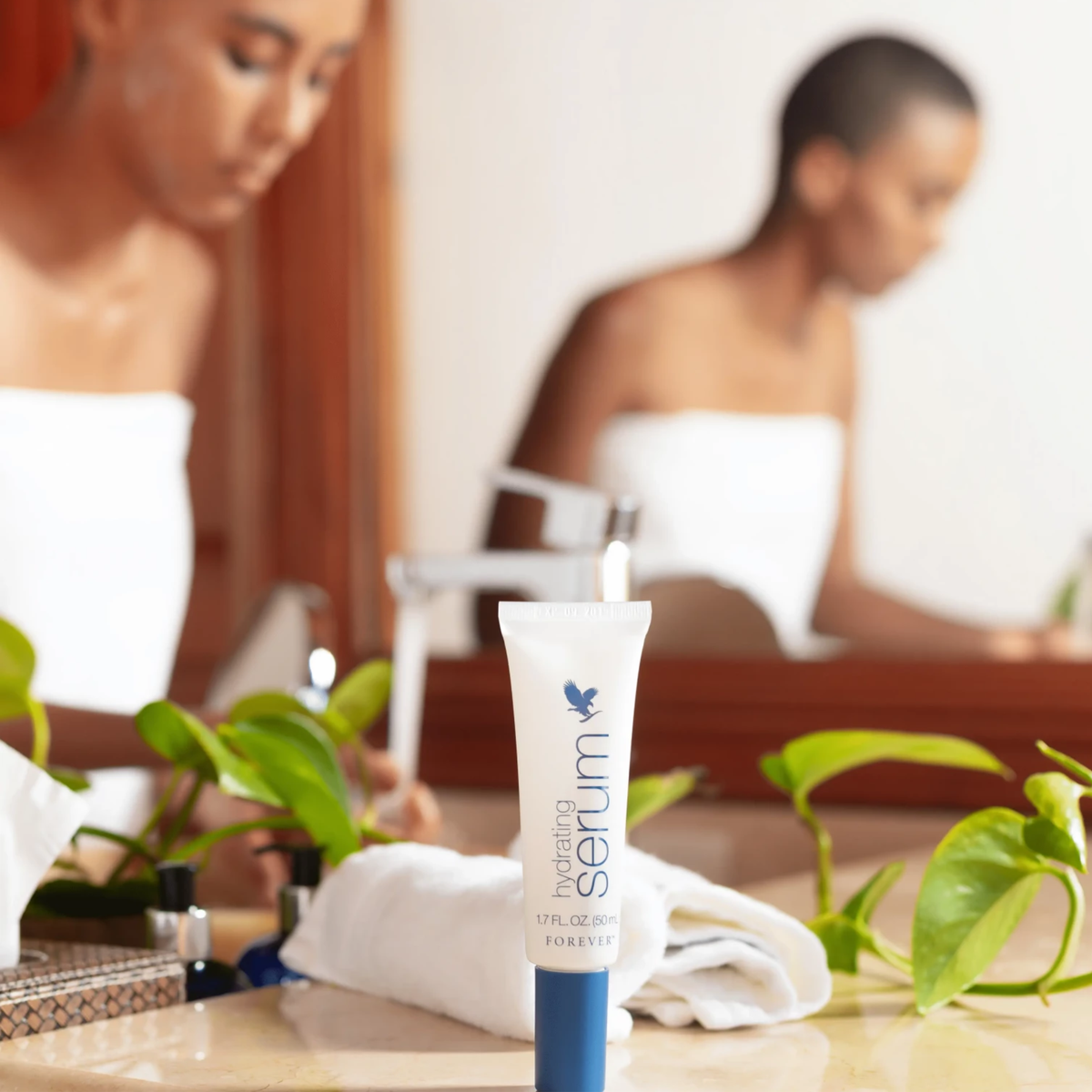 Forever Hydrating Serum présenté avec des feuilles vertes dans une ambiance naturelle évoquant l'aloe vera et l'hydratation.