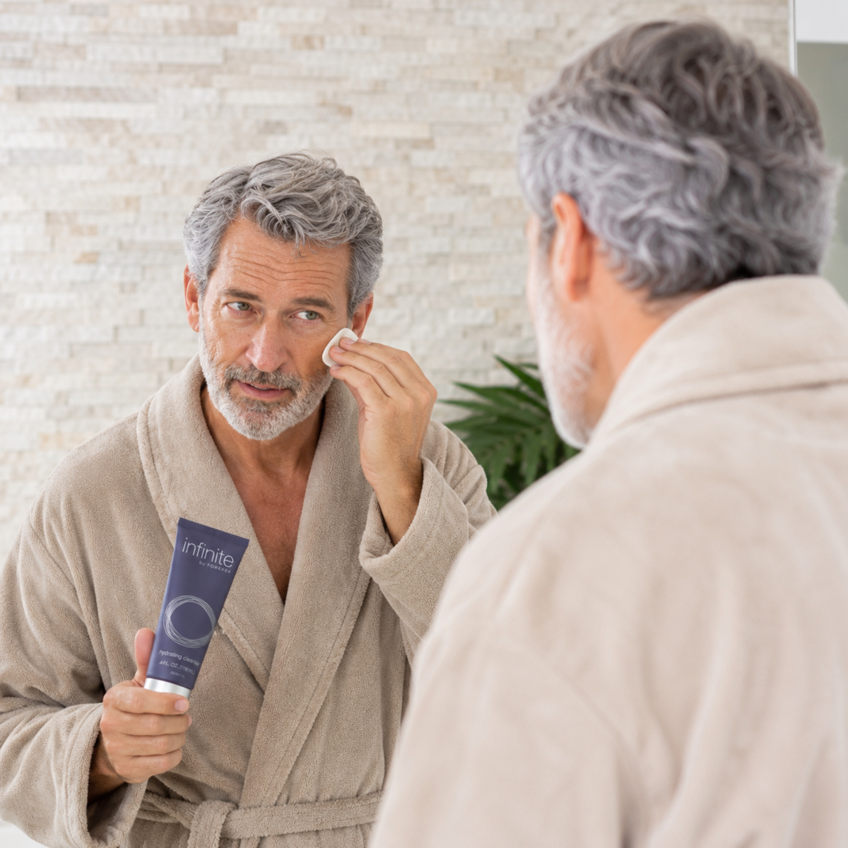 Homme utilisant le Démaquillant Hydratant Infinite Forever dans une salle de bain contemporaine pour nettoyer son visage