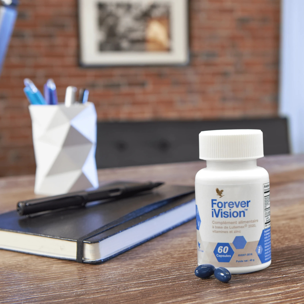 Forever iVision™ posé sur un bureau avec ordinateur et capsules, complément alimentaire pour la vision